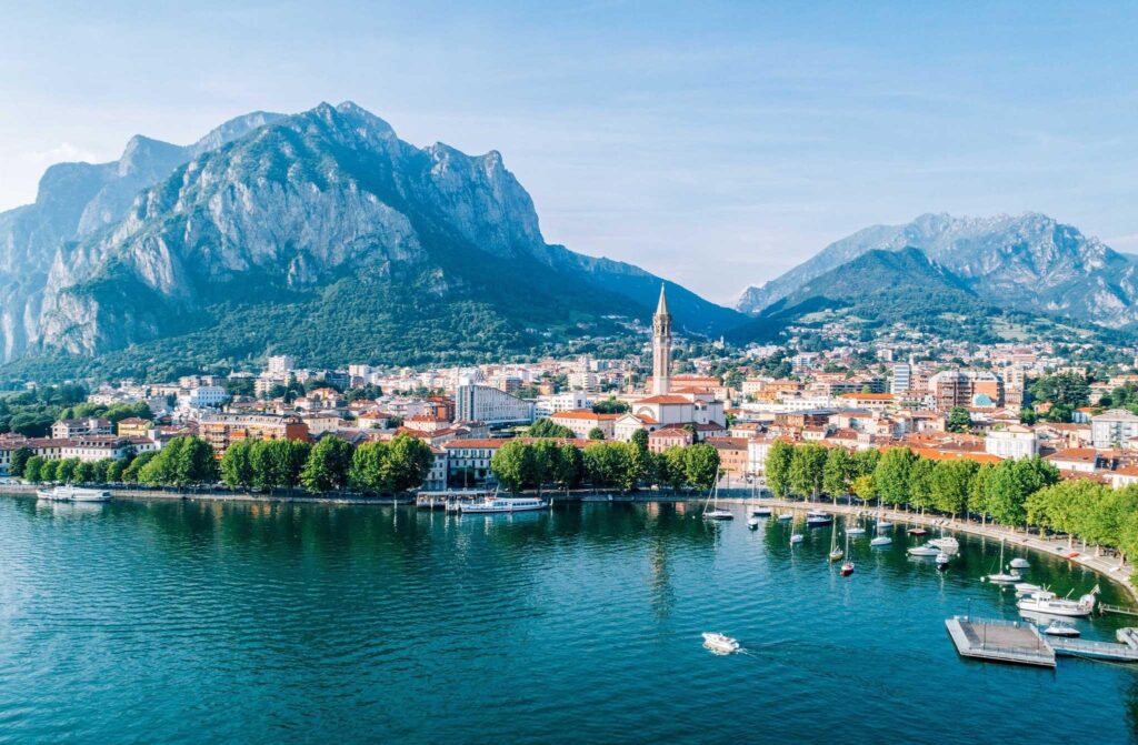Lecco waterfront on Lake Como with the Basilica of San Nicolò bell tower and surrounding mountains